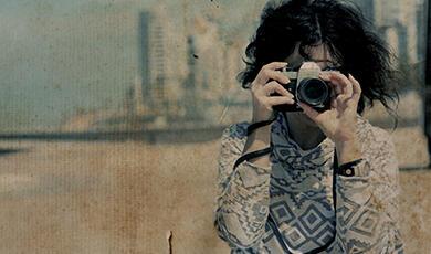 Retro photograph of woman taking a photo with vintage camera on a beach