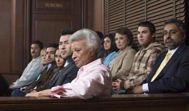A diverse group of jurors of varying ages and ethnicities sits in a courtroom gallery, looking toward the side with serious and attentive expressions