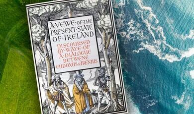 An ornate book cover titled "A View of the Present State of Ireland" sits on a textured surface showing green land on the left and blue sea on the right