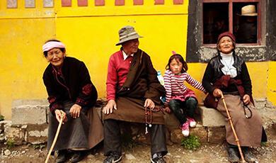 Tibetan family sitting against a yellow wall