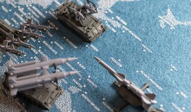 Miniature military vehicle and missile launcher models placed over a blue map of Eastern Europe showing cities like Moscow, Kiev, Warsaw, and Minsk