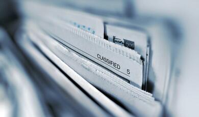 Stack of newspapers from above  with classified pages visible.