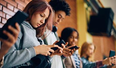 Group of teenagers side on, looking intently at their mobile phones
