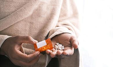 Person taking pills out of bottle