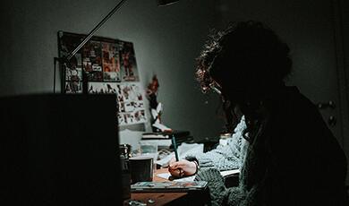 Person writing at desk in darkness