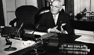 Harry Truman seated at desk in the Oval Office