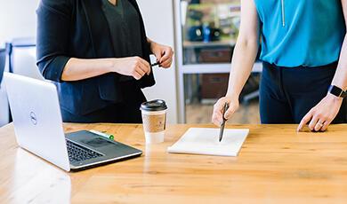 Businesswomen talking, pointing to paper