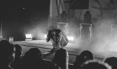 Man crouched into ball on stage