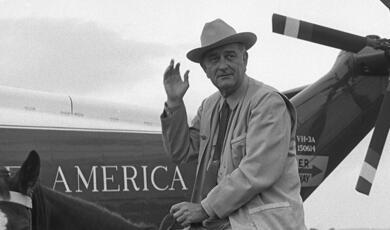 President Lyndon B. Johnson on a horse in front of helicopter