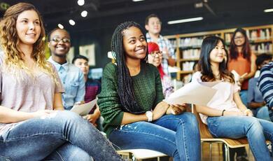 Young people sitting listening to a speaker in a library setting