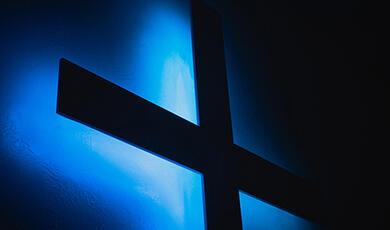 Christian cross back lit by blue light