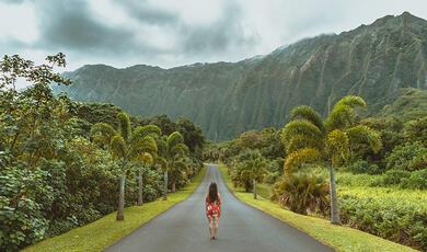 Woman standing on road leading to Hawaiian mountain