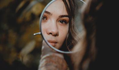 womans face reflected in round mirror
