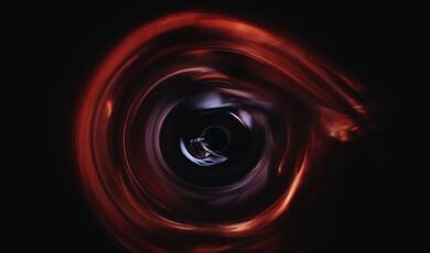 swirling reds and blues with black circle at centre