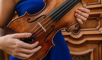 Women in sleeveless blue dress holding violin sideways