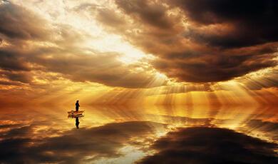 man in a small boat fishing, in distance against sunset