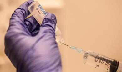 an image of a gloved hand preparing to give an injection